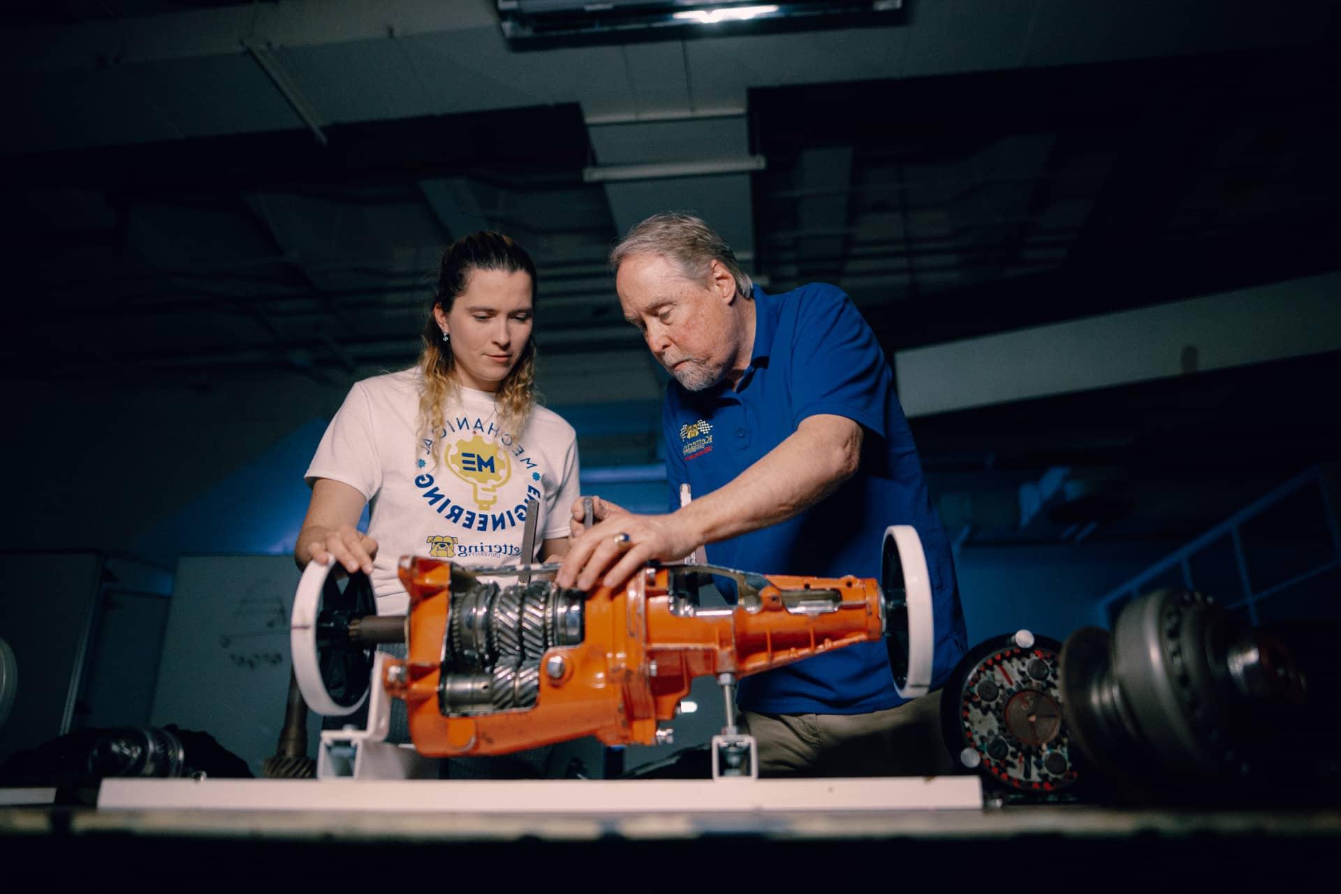 A Kettering professor and mechanical engineering student look at a transmission on display at the Car Lab